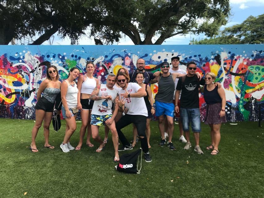 Un viaggio di gruppo WeRoad in posa per una foto su un prato davanti a un muro con graffiti colorati.