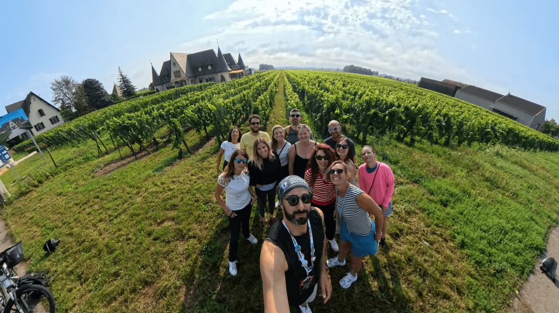 Ein Mann macht ein Selfie seiner WeRoad Gruppenreise, gemeinsam auf einem Weg zwischen Weinreben in einem Weinberg posierend.