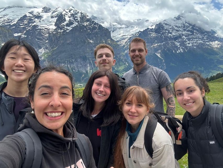 Un groupe WeRoad souriant pour un selfie devant une grande chaîne de montagnes enneigées.