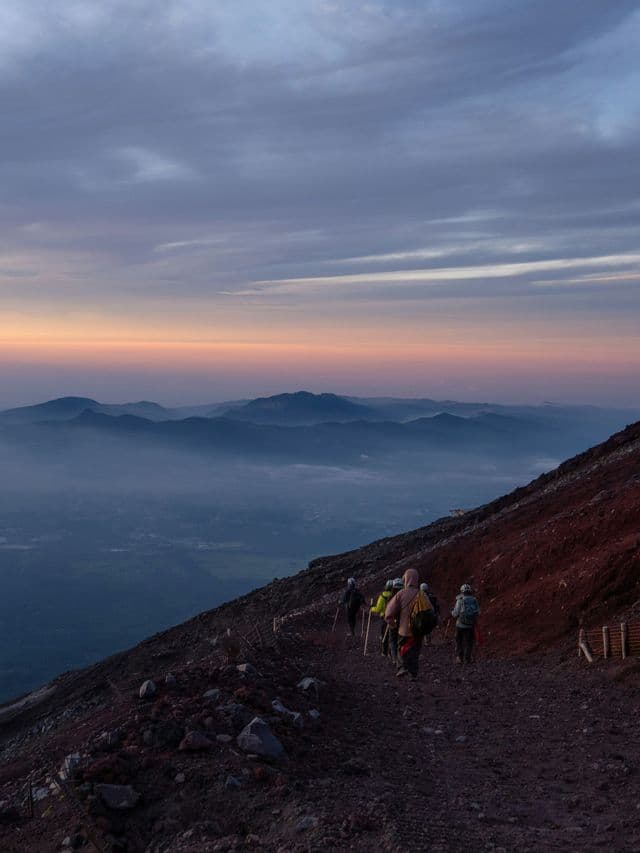 Un viaggio di gruppo WeRoad: escursione all'alba su un pendio montano, con vista su catene montuose avvolte nella nebbia.