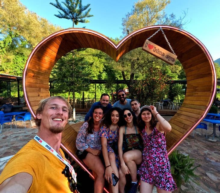 Un groupe WeRoad prend un selfie et pose à l'intérieur d'une grande installation en bois en forme de cœur, entourée d'arbres.