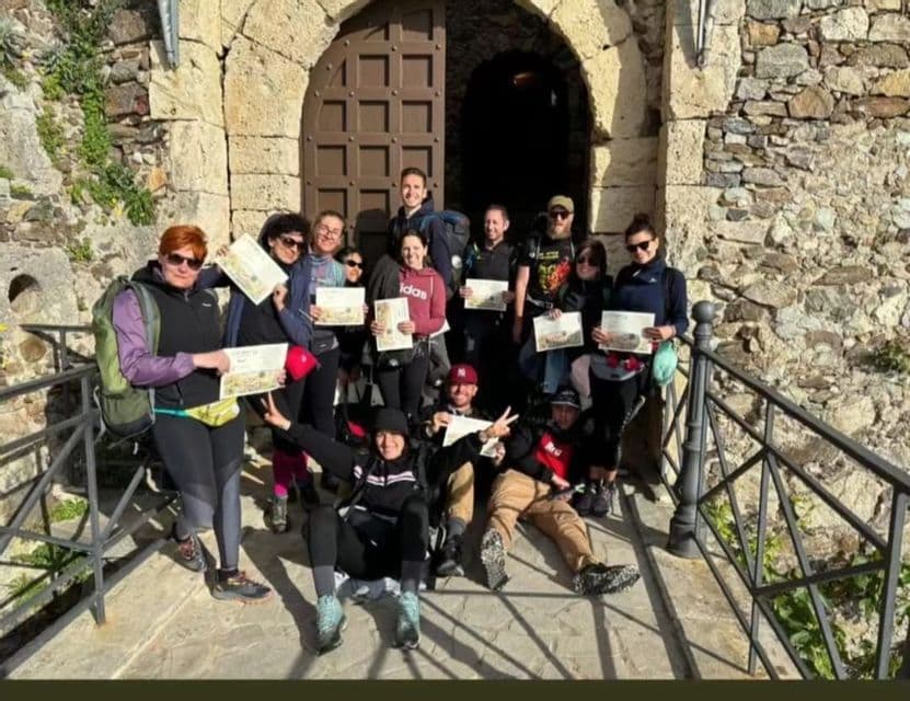 Eine WeRoad Gruppenreise posiert mit Zertifikaten auf einer Steinrampe vor einer gewölbten Holztür eines historischen Gebäudes.