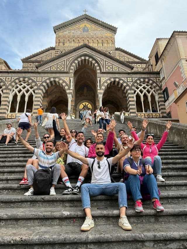 Un viaggio di gruppo WeRoad in posa per una foto sui gradini di pietra davanti a una cattedrale ornata con archi a strisce.