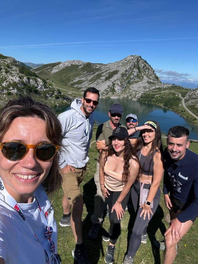 Un grupo de WeRoad sonríe para una selfie frente a un lago de montaña en un día soleado.