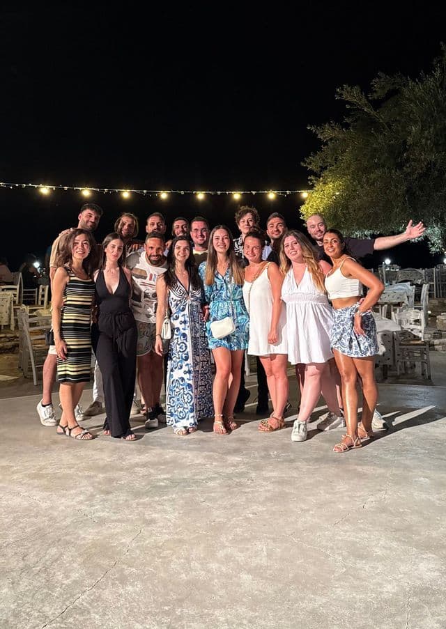 Un gruppo WeRoad in posa per una foto su un patio esterno di notte sotto le lucine.