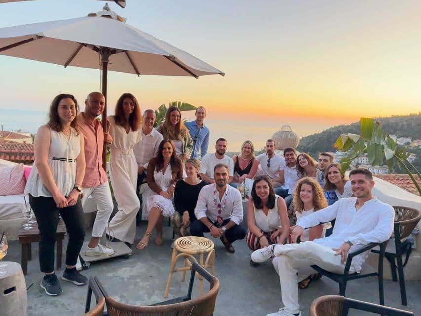 Un viaje en grupo de WeRoad posando para una foto en una terraza en la azotea con vistas al mar al atardecer.