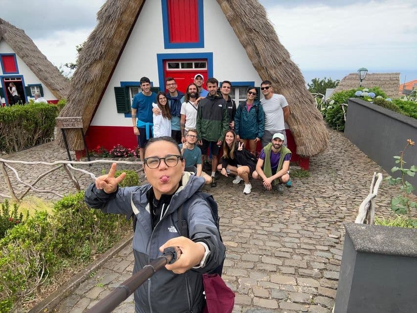 Una donna si scatta un selfie con un viaggio di gruppo WeRoad davanti a tradizionali case a telaio con tetti di paglia.