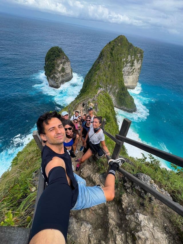 Un gruppo WeRoad si fa un selfie su uno stretto sentiero in cima a una scogliera, affacciato su un oceano turchese e isole rocciose.