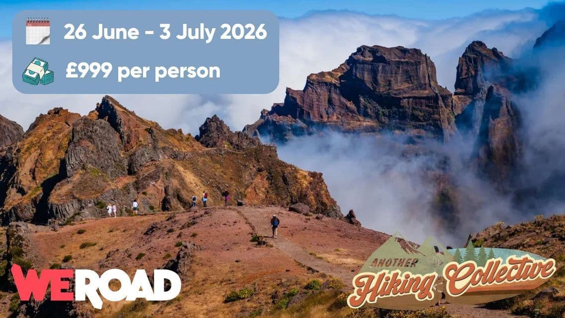 A WeRoad group trip hiking on a rugged mountain trail above a sea of clouds under a clear blue sky.