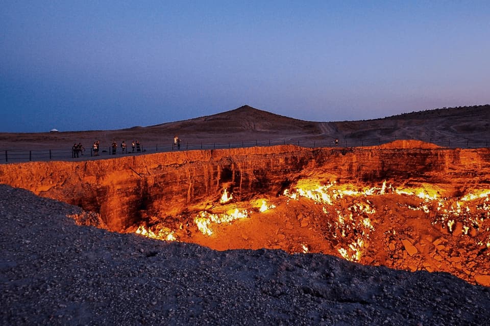 Un viaggio di gruppo WeRoad si trova ai margini di un grande cratere infuocato in un paesaggio desertico al tramonto.