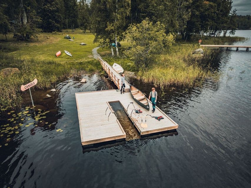 Luftaufnahme von zwei Personen einer WeRoad-Gruppenreise, die ein Kanu an einem Holzsteg an einem See vorbereiten.