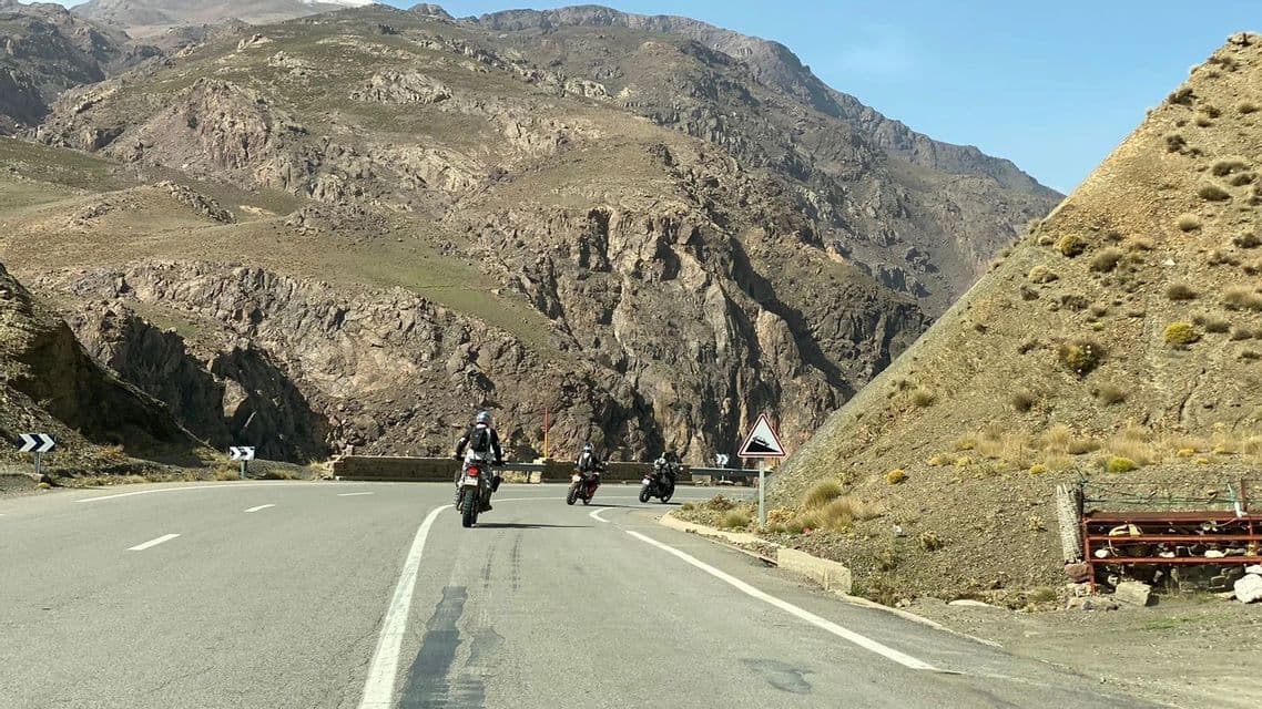 Un viaggio di gruppo WeRoad in moto su una strada tortuosa attraverso un vasto e roccioso paesaggio montano.