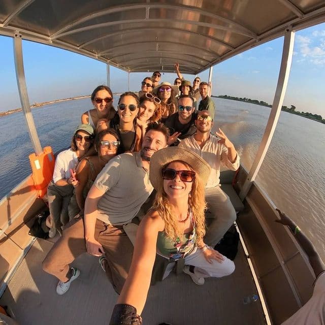 Una donna scatta un selfie del suo viaggio di gruppo WeRoad mentre sorridono e posano su una barca coperta su un fiume.