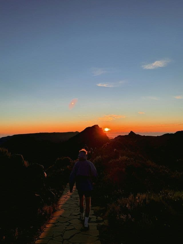 Eine WeRoad Gruppenreise wandert auf einem Steinpfad in den Bergen zum Sonnenaufgang.