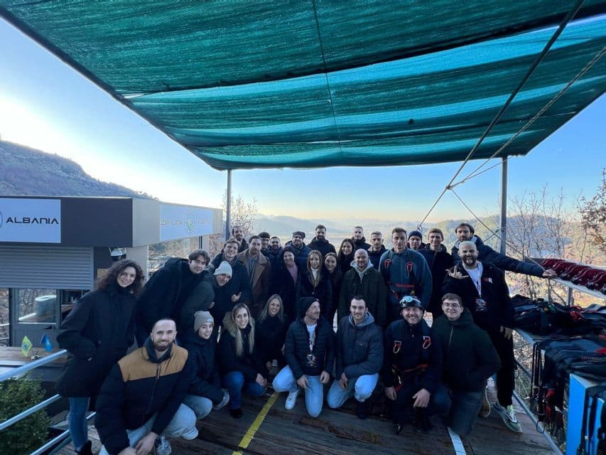 Un gruppo WeRoad in posa per una foto su una piattaforma di legno sotto una tenda verde, con montagne sullo sfondo.