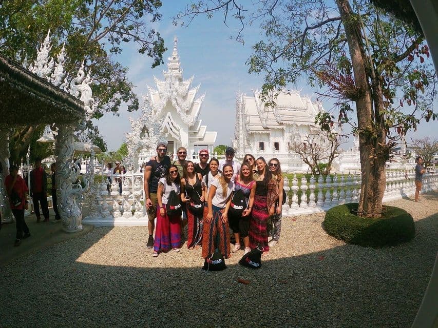 Un gruppo WeRoad in posa per una foto davanti a un tempio bianco decorato sotto un cielo azzurro e limpido.