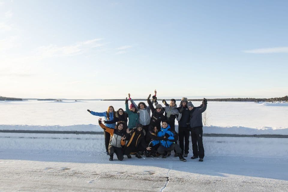 Un viaje en grupo de WeRoad con ropa de invierno posando para una foto en un vasto paisaje nevado bajo un cielo despejado.