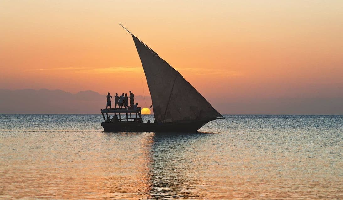 Un viaje en grupo de WeRoad silueteado en un velero tradicional, flotando en el mar durante un atardecer dorado.