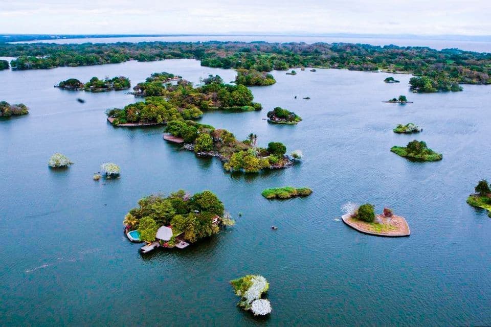 Vista aerea di molte piccole isole verdi sparse su una vasta distesa di acqua blu sotto un cielo coperto.