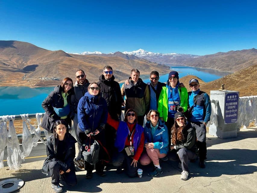 Un gruppo WeRoad in posa per una foto con vista su un lago turchese e montagne innevate sullo sfondo.