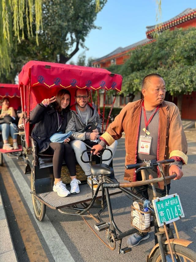 Due persone di un viaggio di gruppo WeRoad sorridono su un risciò con baldacchino rosso durante un tour della città.