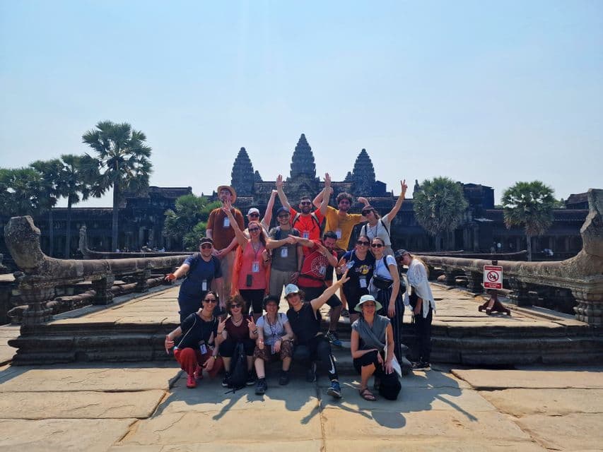 Un viaggio di gruppo WeRoad in posa per una foto su una passerella in pietra davanti a un tempio antico sotto un cielo sereno.