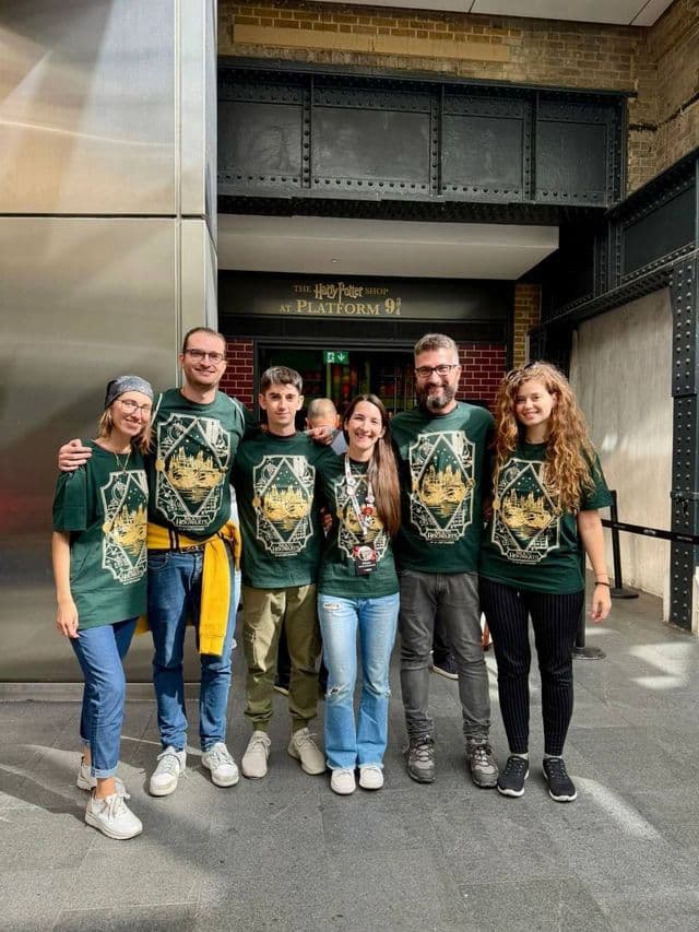Un gruppo WeRoad in viaggio con magliette verdi abbinate, in posa davanti all'ingresso del negozio di Harry Potter.