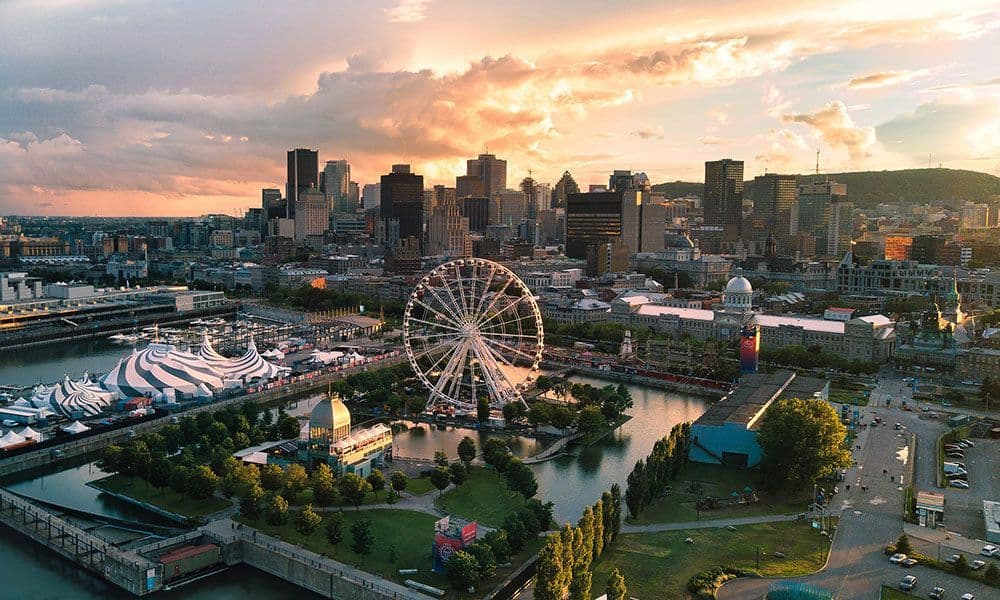 Vue aérienne d'un horizon urbain avec une grande roue et un port lors d'un coucher de soleil doré.