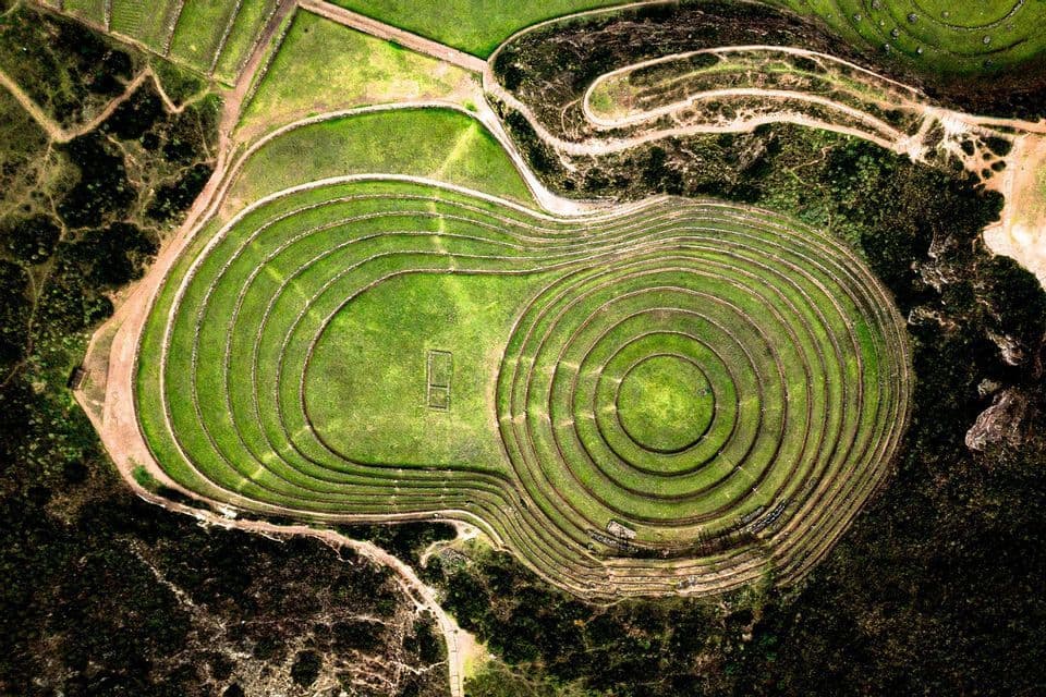 Vista aérea de antiguas terrazas agrícolas circulares talladas en el verde paisaje.