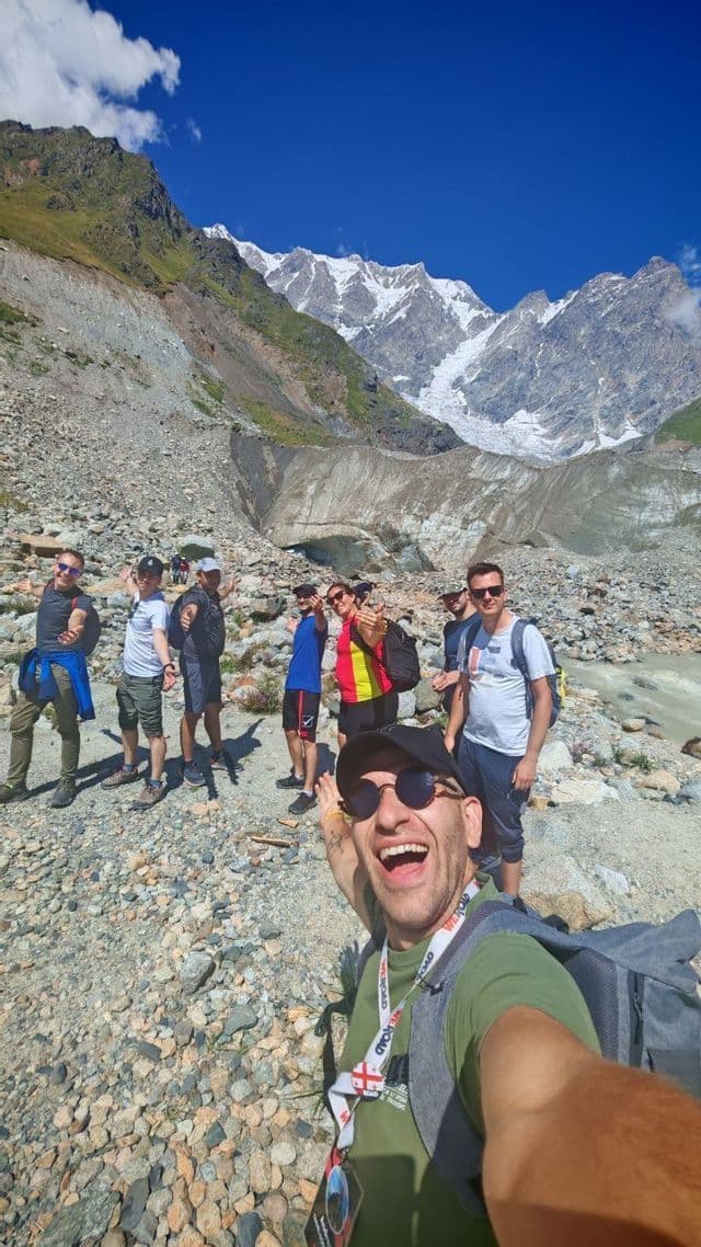 Un uomo si scatta un selfie durante il suo viaggio di gruppo WeRoad su un sentiero roccioso, con le montagne innevate sullo sfondo.