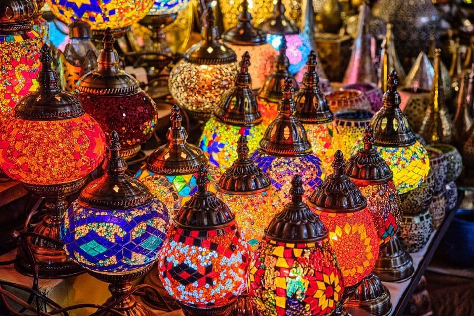 Une collection dense de lampes colorées en mosaïque de verre, aux motifs complexes, illuminées et rayonnantes, exposées.