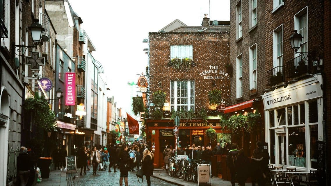 Eine belebte Kopfsteinpflasterstraße mit Menschen vor der Backsteinfassade des Temple Bar Pubs, geschmückt mit Lichterketten.