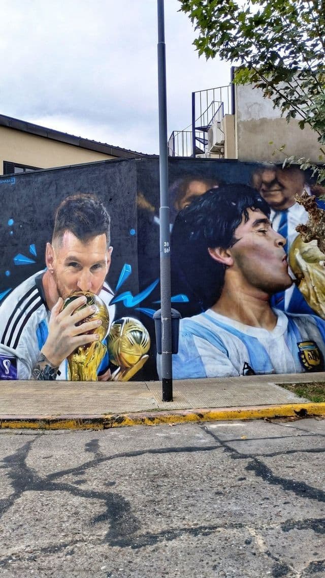 Un murale di street art che raffigura i calciatori Lionel Messi e Diego Maradona con le maglie dell'Argentina, entrambi mentre baciano un trofeo della Coppa del Mondo.