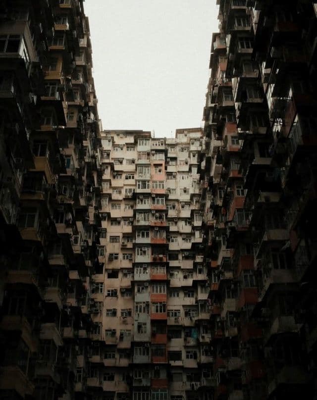Una vista dal basso da un cortile stretto verso le facciate fitte e sovrapposte di alti condomini.