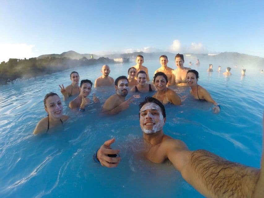 Un gruppo WeRoad si fa un selfie mentre fa il bagno in una laguna geotermica blu con maschere bianche.