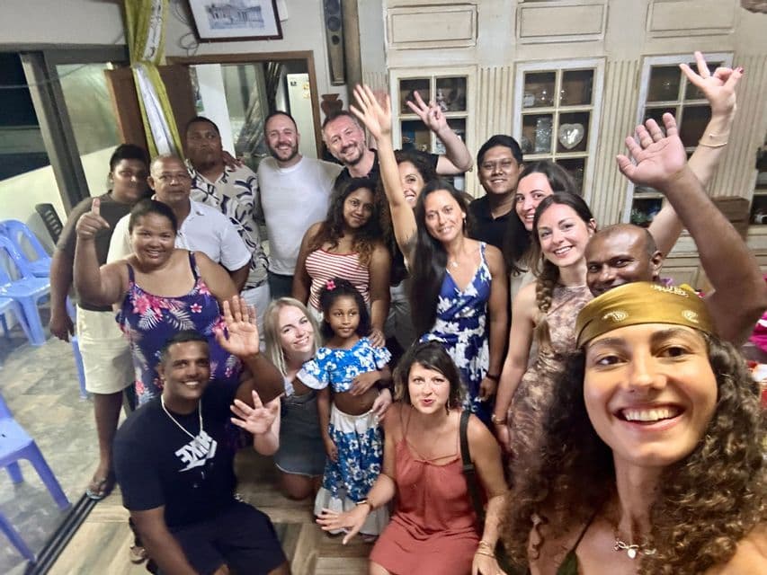 Un grand groupe WeRoad en voyage, dont une jeune fille, prend un selfie souriant ensemble, à l'intérieur, de nuit.