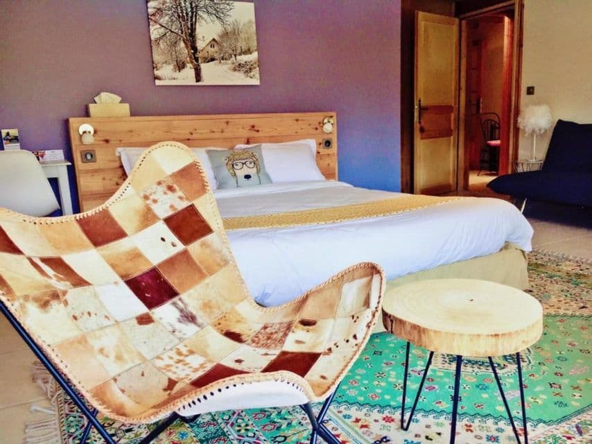 Une chambre rustique dotée d'un fauteuil papillon en cuir patchwork, d'une table d'appoint en rondin de bois et d'un lit avec une tête de lit en bois.