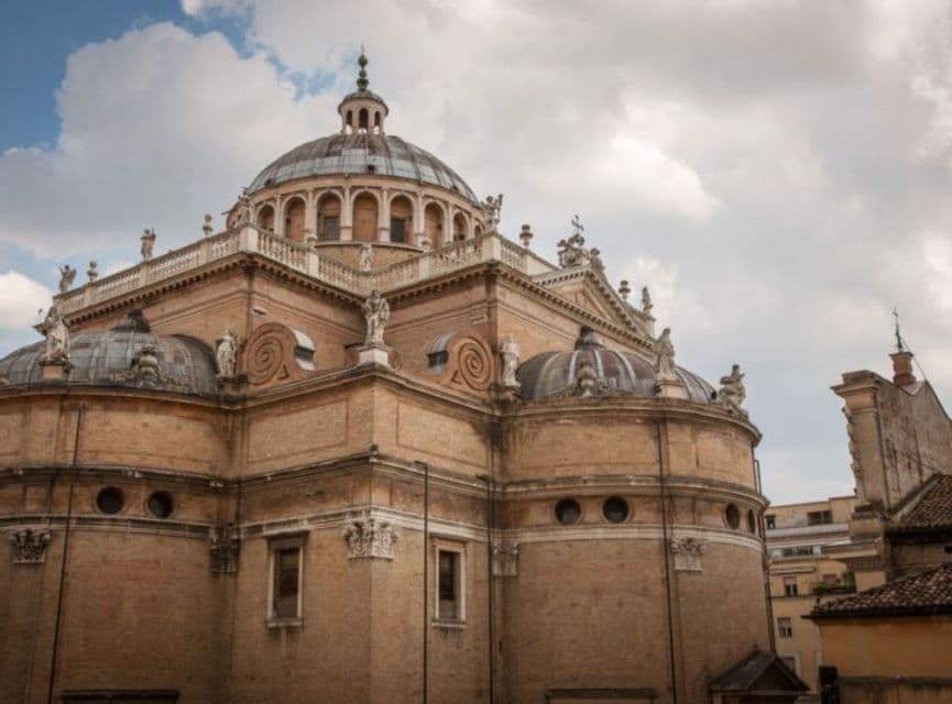 Una grande basilica in mattoni, con cupole multiple e statue ornate, sotto un cielo parzialmente nuvoloso.