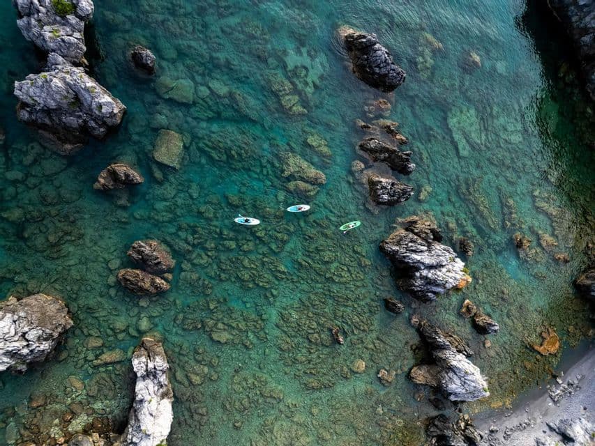 Vista aerea di un gruppo WeRoad che fa paddleboard in acque limpide e turchesi tra grandi formazioni rocciose.