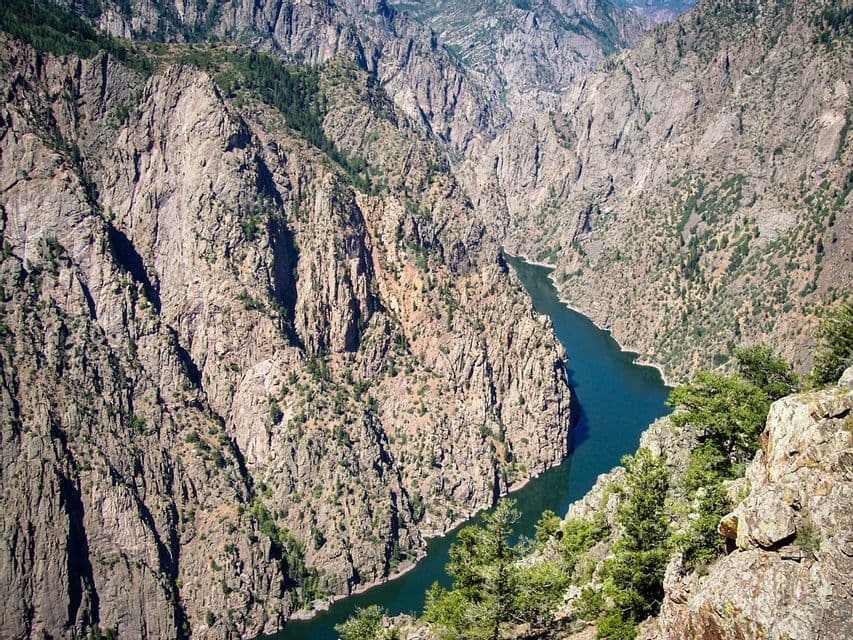 A high-angle view of a river winding through a steep, rocky canyon with sparse green vegetation.