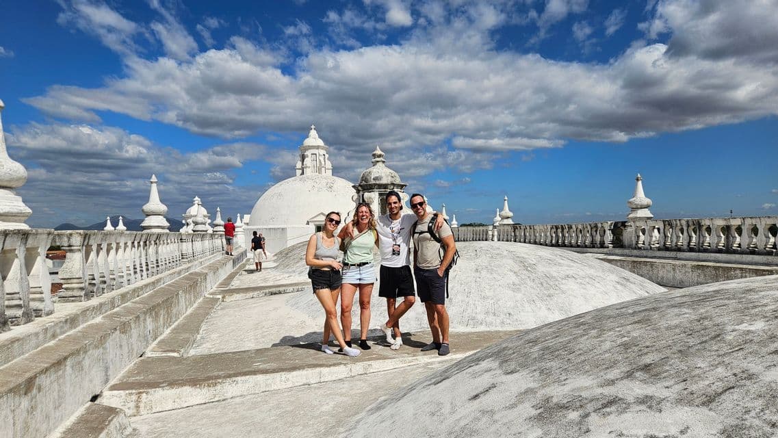 Eine WeRoad-Gruppe von vier Personen posiert auf dem weißen Kuppeldach eines Gebäudes unter blauem Himmel mit Wolken.