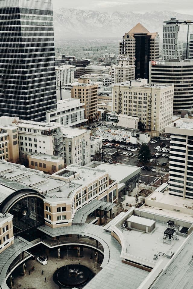 A high-angle view of a dense cityscape with numerous buildings and skyscrapers, with a mountain range visible in the distance.