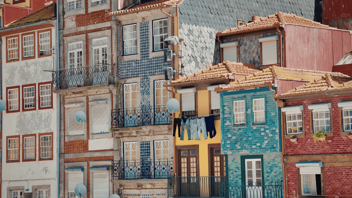 Un gruppo fitto di edifici colorati, con facciate piastrellate a motivi diversi e bucato steso su un filo tra due case.