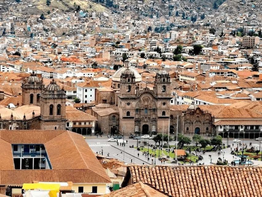 Una vista aerea di una città con tetti rossi, una cattedrale centrale in pietra e una vivace piazza su una collina.