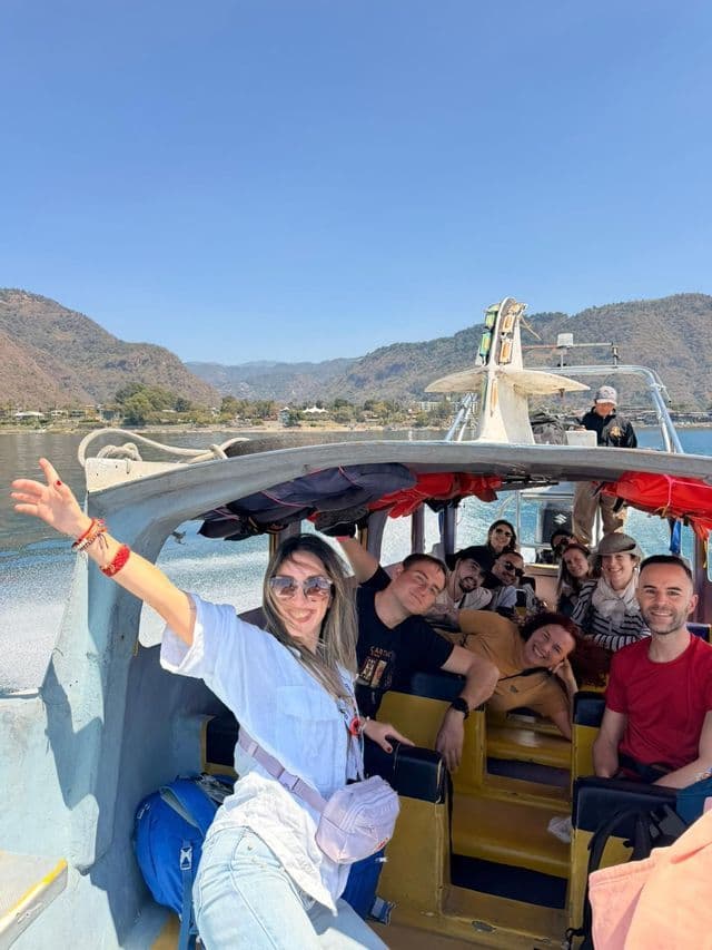 Un grupo sonriente de WeRoad posando para una foto en una lancha motora, con montañas de fondo bajo un cielo azul despejado.