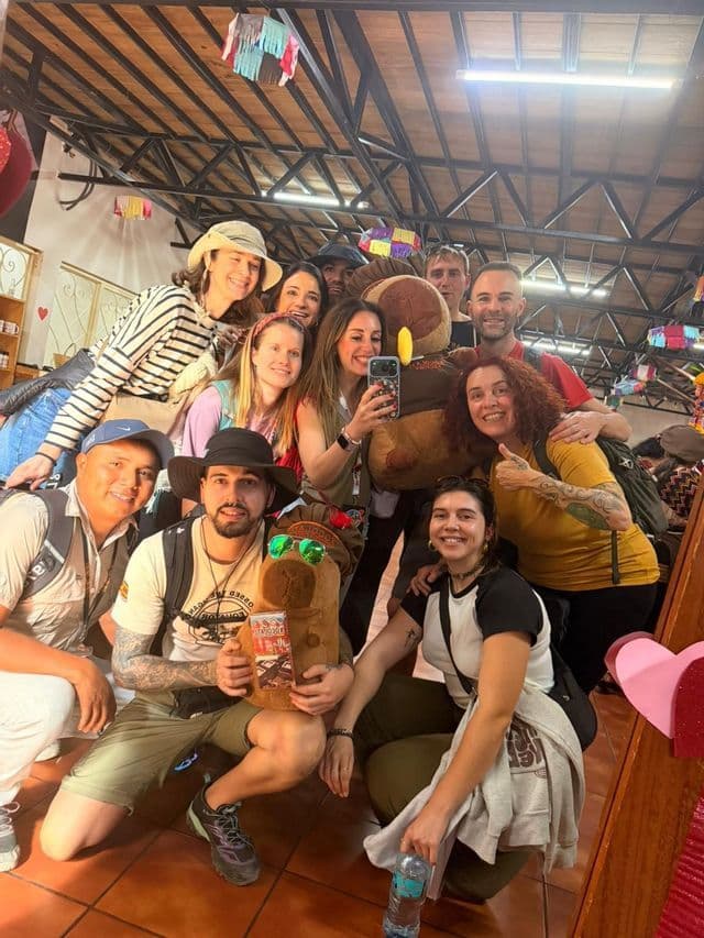 Un viaje en grupo de WeRoad se toma una selfie grupal en un espejo posando con una mascota de peluche.