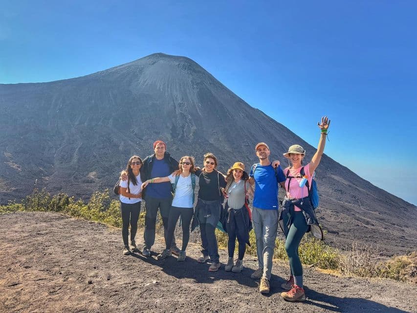 Un grupo de WeRoad posa para una foto en una ruta de senderismo con un gran volcán al fondo.