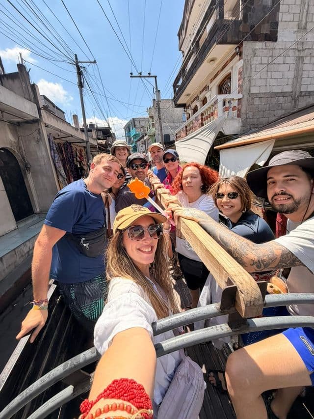 Un viaje en grupo de WeRoad se toma una selfie desde la parte trasera de un vehículo descapotable mientras recorre una calle estrecha del pueblo.