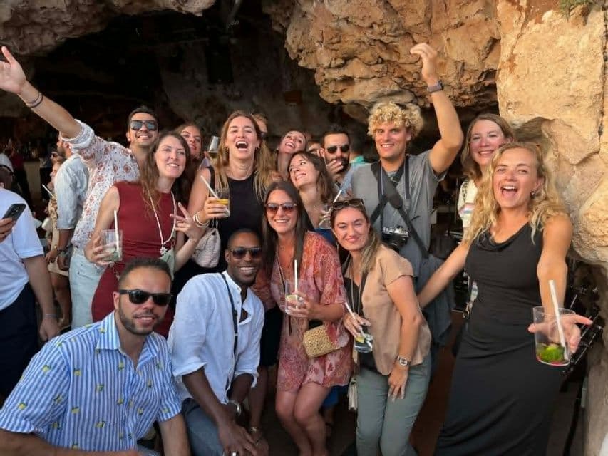 Un voyage de groupe WeRoad : des personnes souriantes posent avec des boissons dans une grande grotte rocheuse.
