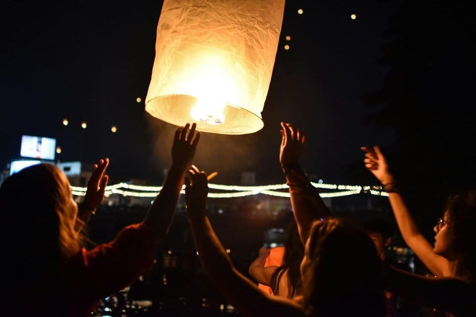 Un gruppo WeRoad, le cui sagome si stagliano su una grande lanterna di carta illuminata che stanno rilasciando nel cielo notturno.